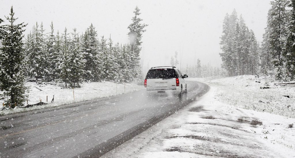 Voiture qui roule sur une route enneigée