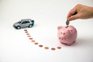 Tirelire rose en forme de cochon avec argent autour et figurine voiture